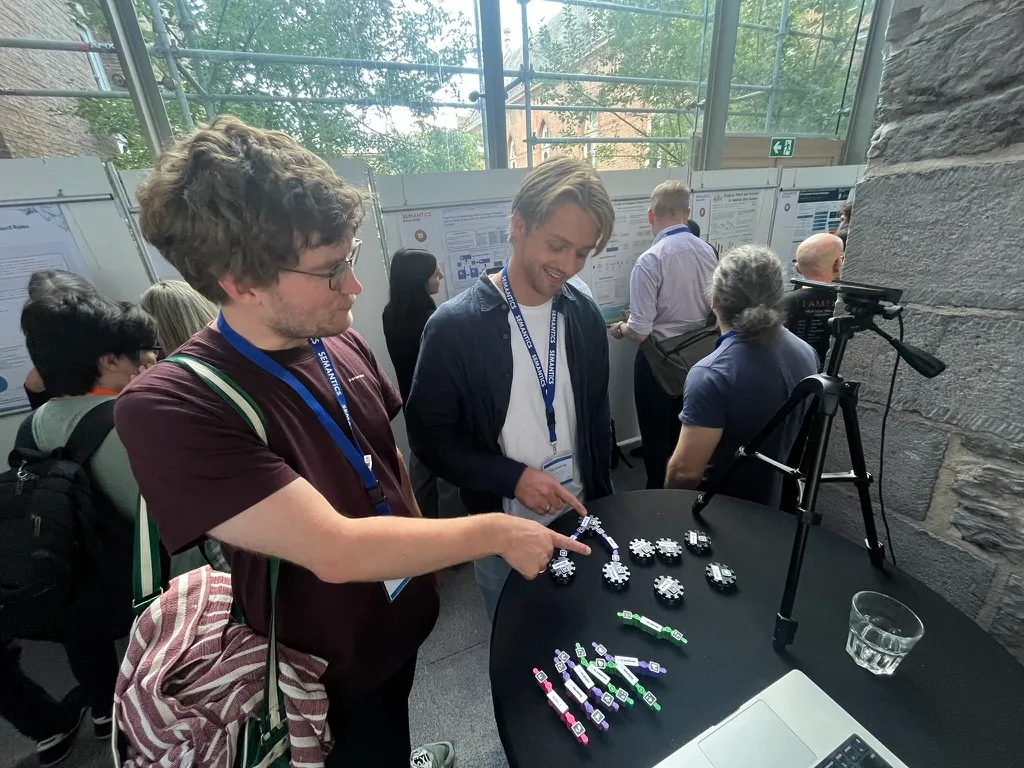 Two attendees leaning over the demo table, one adjusting a piece of the graph.