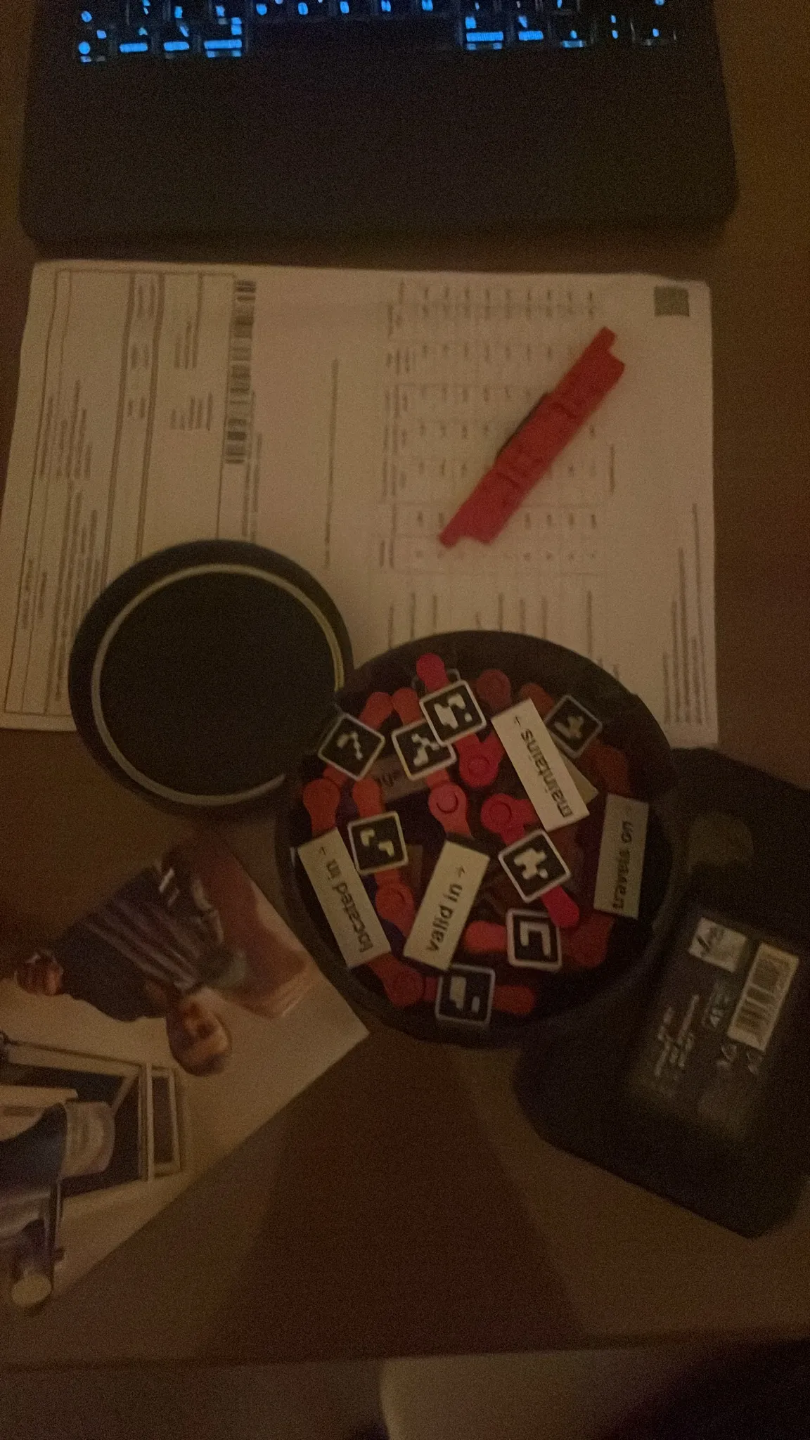 A tray of red ArcUno pieces with printed labels and marker tags on a desk.
