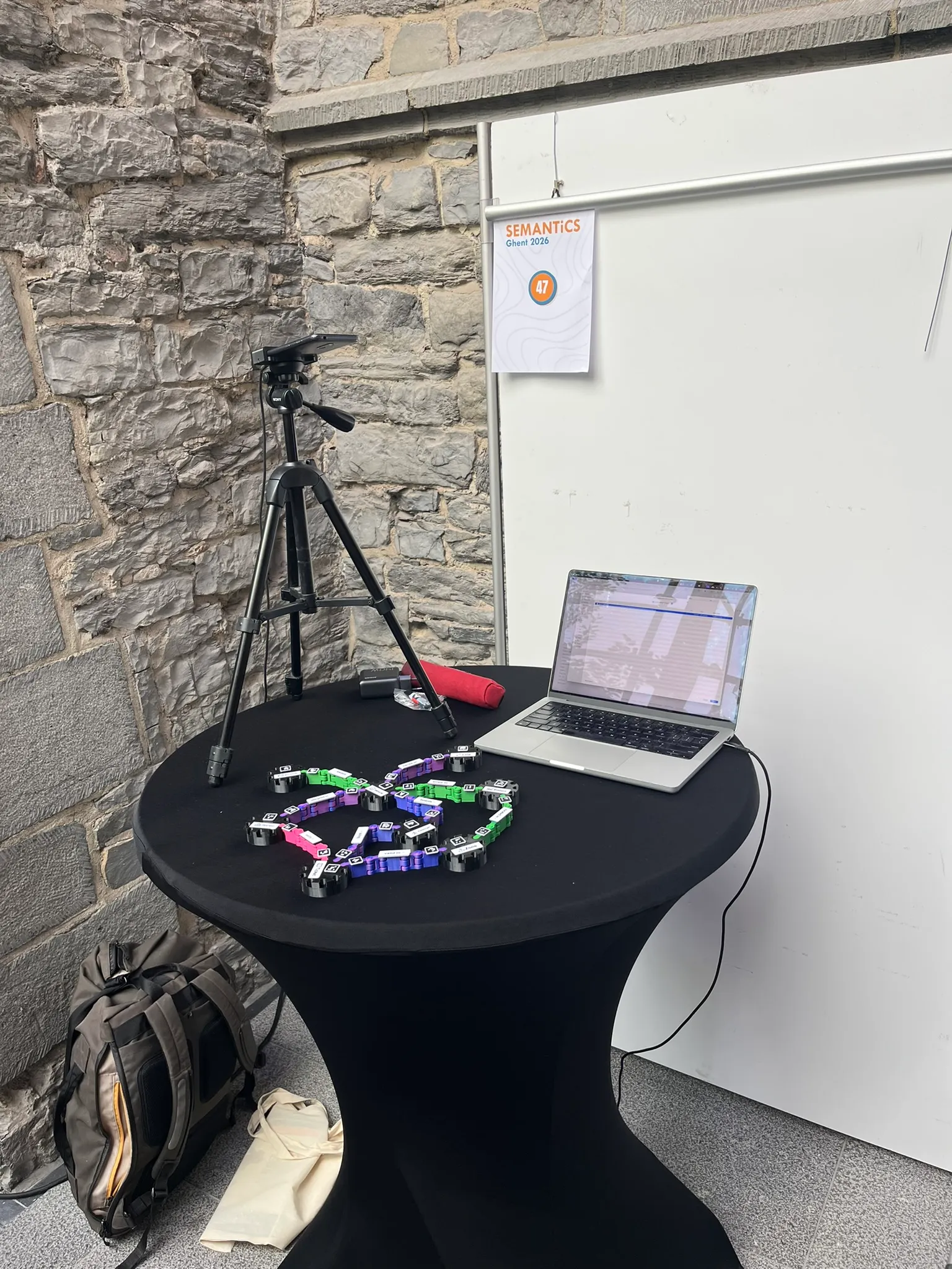 The demo table: a phone on a tripod above a colorful graph, a laptop beside it, against a stone wall.