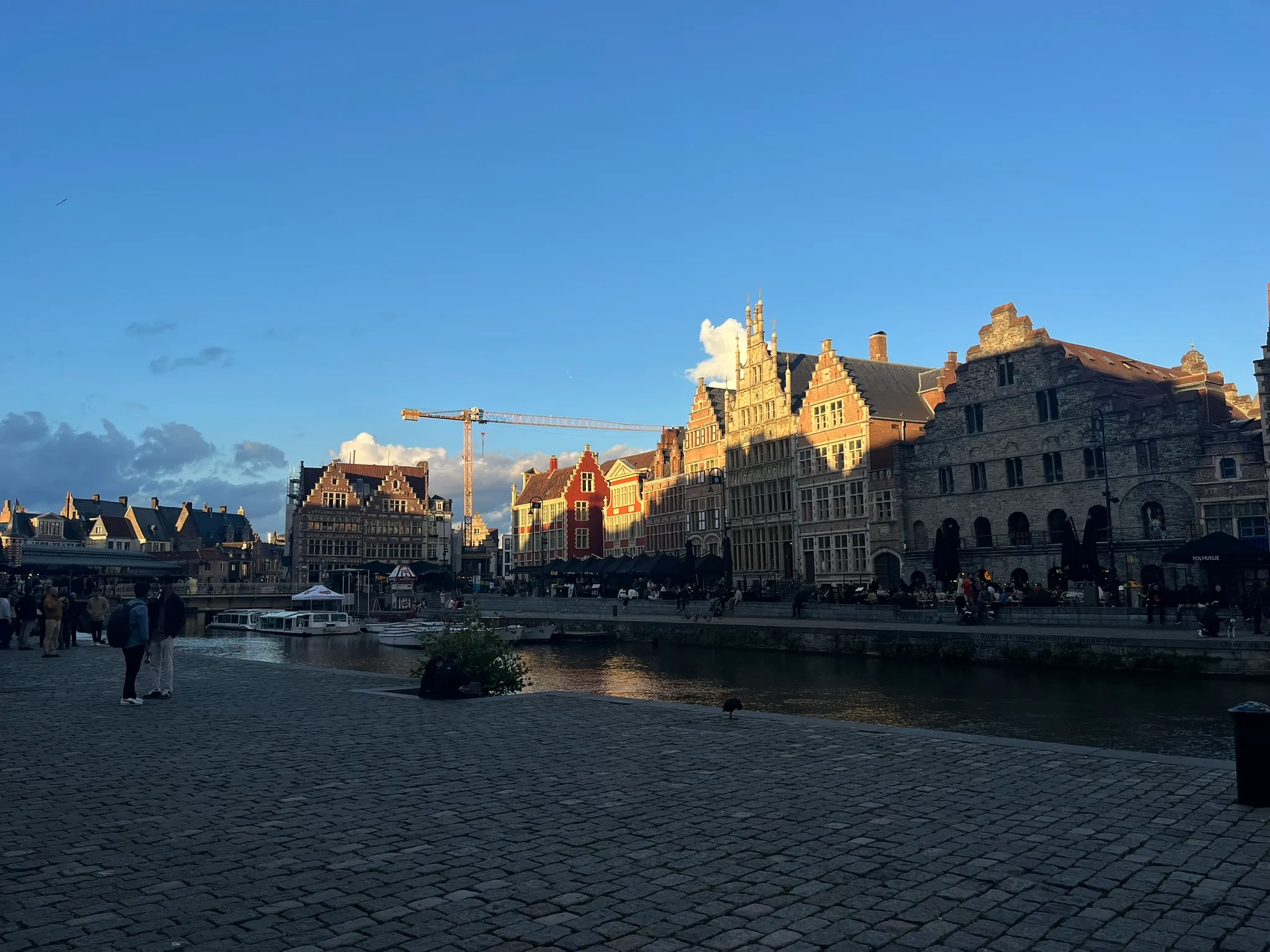 Gabled historic buildings along the Ghent waterfront in low evening sun.